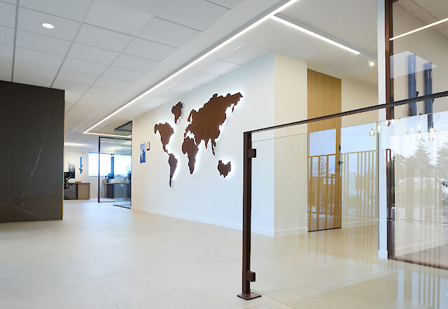 Entrance area with world map on the wall and linear ceiling lighting in the renovated Apageo headquarters