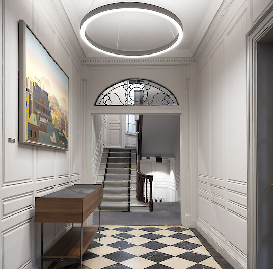 Elegant hallway with black and white tiled floor, classic wall design and ring-shaped Ringo Star pendant luminaires.
