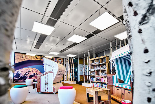 Creatively designed room with beach chairs, birch trunks, bookshelves and square cubic pendant luminaires.