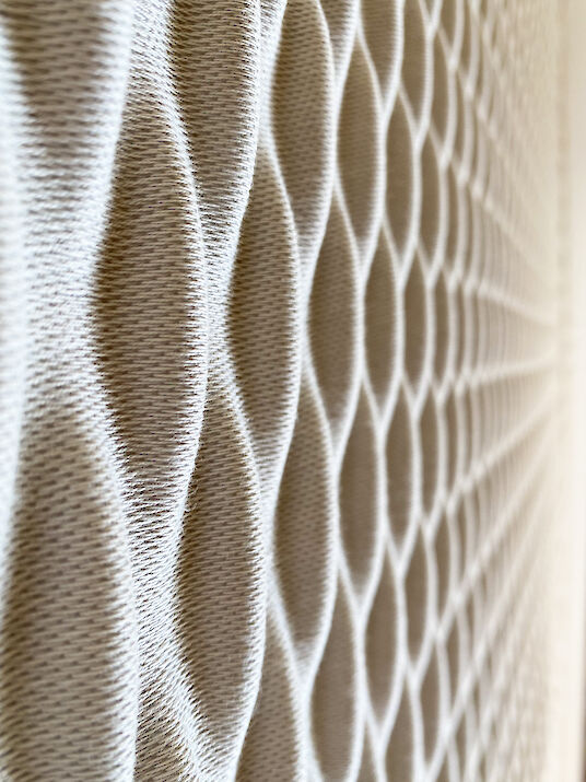 Close-up of a structured acoustic material with a honeycomb pattern and soft, textile surface.